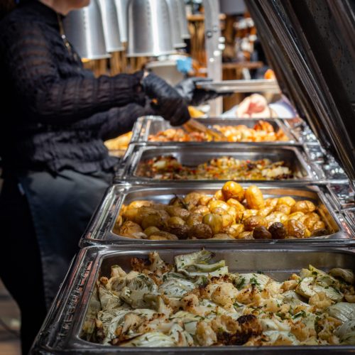 Employé servant un plat parmi un étalage de produits frais à La Focacceria